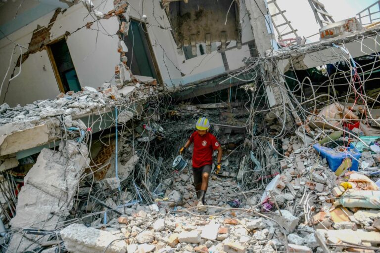 CH11358579_AGENCY PHOTO SEE RESTRICTION - A rescuer carries equipment as a team searches through the rubble of a destroyed building in Mandalay, Myanmar. Gaza-Israel_Thumbnail